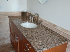 Granite top vanity and decorative tilework in guest bath.